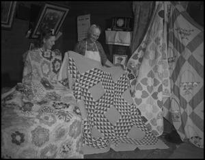 [Two women showing off their quilts]