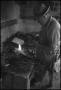 Photograph: [Photograph of a man firing up his forge]