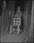 Photograph: [Girl standing behind a chair]