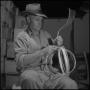 Photograph: [Photograph of a man tying wooden hoops together]