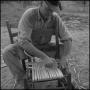 Photograph: [Photograph of a man weaving the seat of a chair, 1]