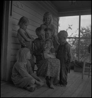 [Photograph of five children watching their grandmother feed a baby, 1]