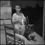 Photograph: [Photograph of a man weaving a basket with his dog]
