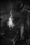 Photograph: [Photograph of a man pouring water over a fire, 1]