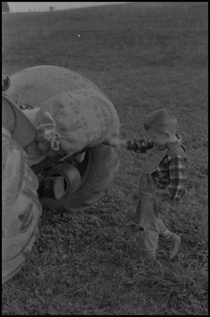 [Photograph of a young boy standing next to a tractor]