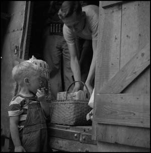 [Photograph of a young man giving a basket to a young boy]
