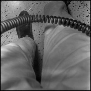 [Photograph of a pair of legs and a telephone cord]