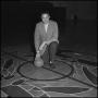 Photograph: [Head Coach Charles Johnson kneeling with a basketball]