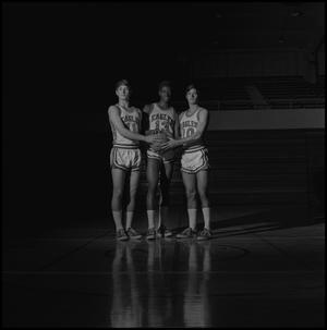 [Three basketball players holding onto ball together]