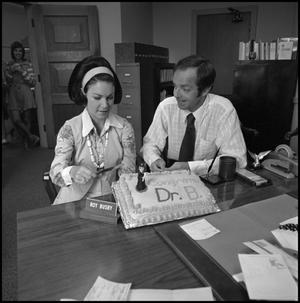 [Dr. Roy K. Busby sitting with cake]