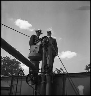 [Two men standing on top of a trailer]