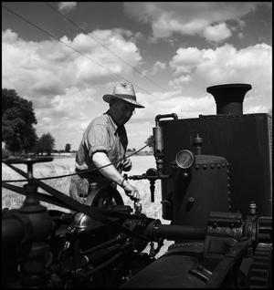 Primary view of object titled '[Man adjusting a knob on an engine]'.