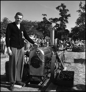 [Close up of a young man standing next to an engine]