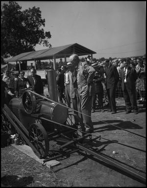 [People looking at a small locomotive engine]