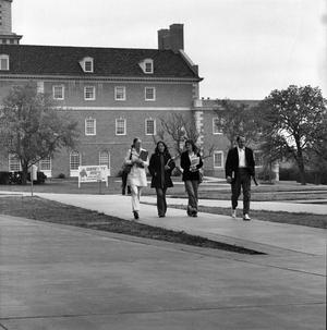 [Four people walking in front of the Hurley Administration Building]