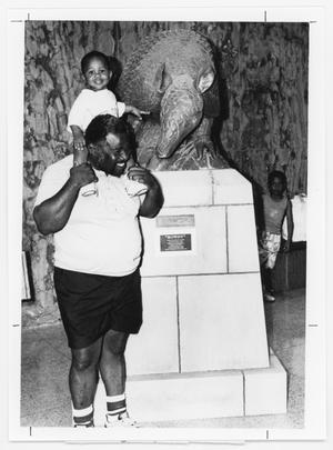 [Man and Child Standing Next to an Armadillo Statue]