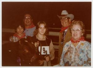 [Frank Cuellar Sr., Julia Cuellar, Frank III (grandson) and Frank Jr. posing with cow]