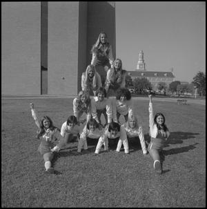 [Cheerleaders pose in pyramid]