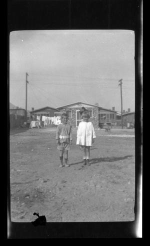 [Children standing outside of a house]