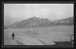 [Man walking along the Rhine River across from Ehrenbreitstein Fortress in Koblenz, Germany]