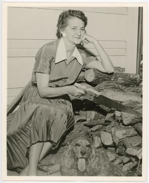 [Dorothy Babb sitting on a wood pile with her dog]