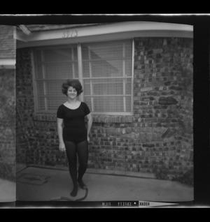 [Photo of a woman standing in front of a house]