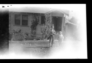 [Two boys standing in front of a house]