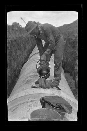 [A man standing on an underground pipe]