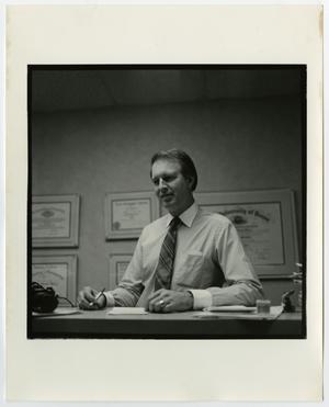 [Photograph of a man seated at desk]