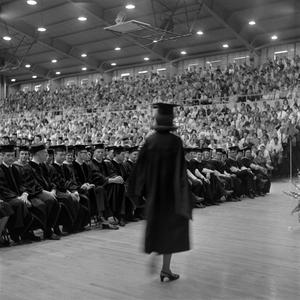 [A young woman walks to receive diploma]