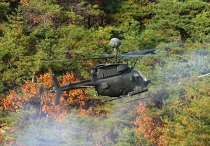 [Photograph of a black helicopter flying over a forest]