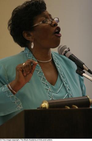 [Woman addressing audience at ladies luncheon]