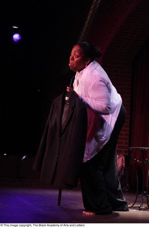 [Performer on stage holding a coat]