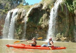 [Two women kayaking near a waterfall]