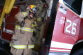 Primary view of [A fireman puts on his helmet while standing beside fire engine #26]