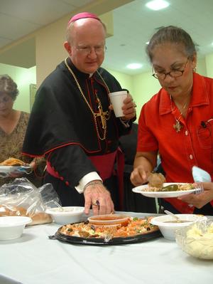 [Bishop Kevin Vann and women at table of food]