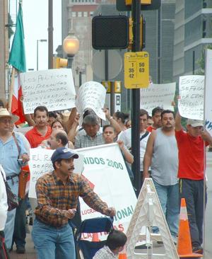 [Protesters carry signs and the Mexican Flag]