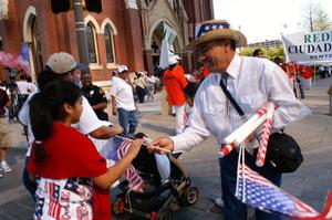 [Man gives a girl an American flag in front of Cathedral Santuario de Guadalupe]