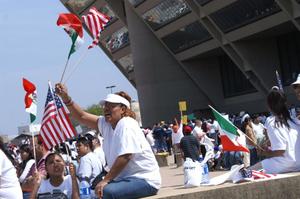 [A woman raises a United States and Mexican flag in front of Dallas City Hall]
