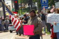 Photograph: [Male Protester Holding Bright Pink Sign and American Flag]