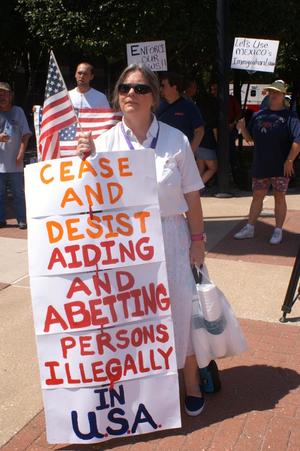 Primary view of object titled '[Protester holding an anti-immigration sign]'.