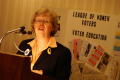 Thumbnail image of item number 1 in: '[Woman stands at a podium with a microphone, speaking, with a sign behind her]'.