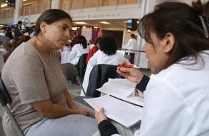 Primary view of object titled '[A woman listens to another woman in a white coat in what appears to be a medical consultation]'.