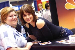 [Gabriela leans over table to take photo with fan]