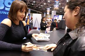 [A woman smiles while Gabriela Spanic gives her an autograph]