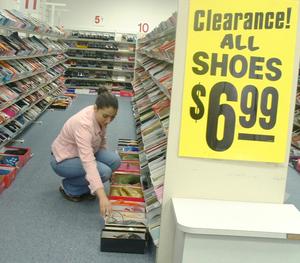 [Woman kneeling next to shelves of shoes]