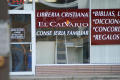 Photograph: [Glass facade of Christian bookstore with Spanish signage]