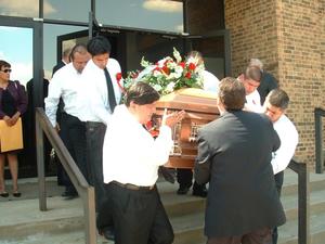[Men carrying casket down stairs and out of building]