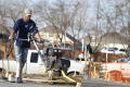 Primary view of [Man in blue shirt pushing heavy equipment]